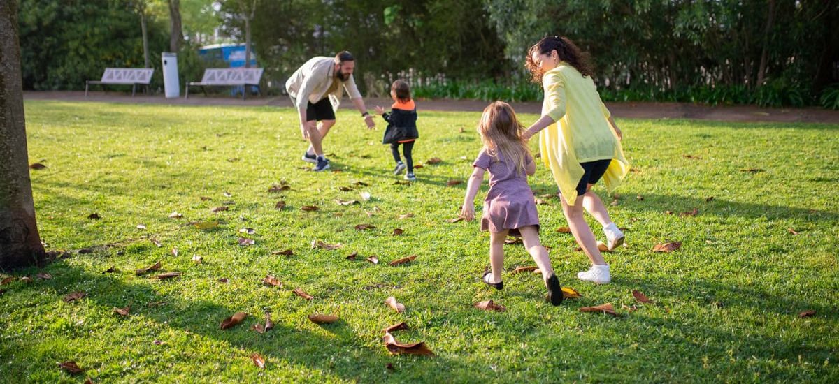 A joyful family playing together in a lush green park setting, enjoying a bright day.