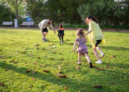 A joyful family playing together in a lush green park setting, enjoying a bright day.